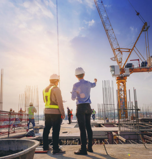 Structural engineer and foreman worker with touch pad discuss, plan working for the outdoors building construction site.